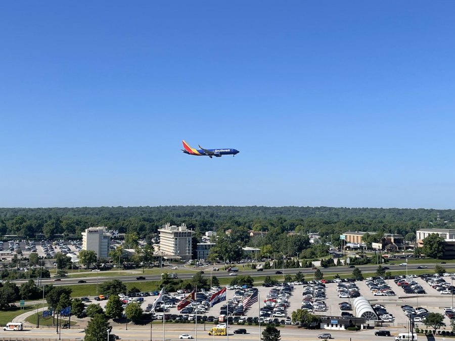 A Southwest plane flys above the airport in a very clear blue sky