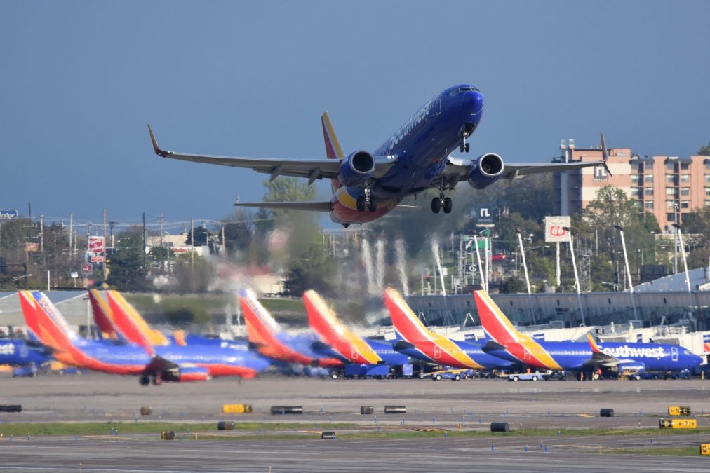 Photo of a multicolored Southwest plane taking off with multiple other Southwest planes lined up in the background