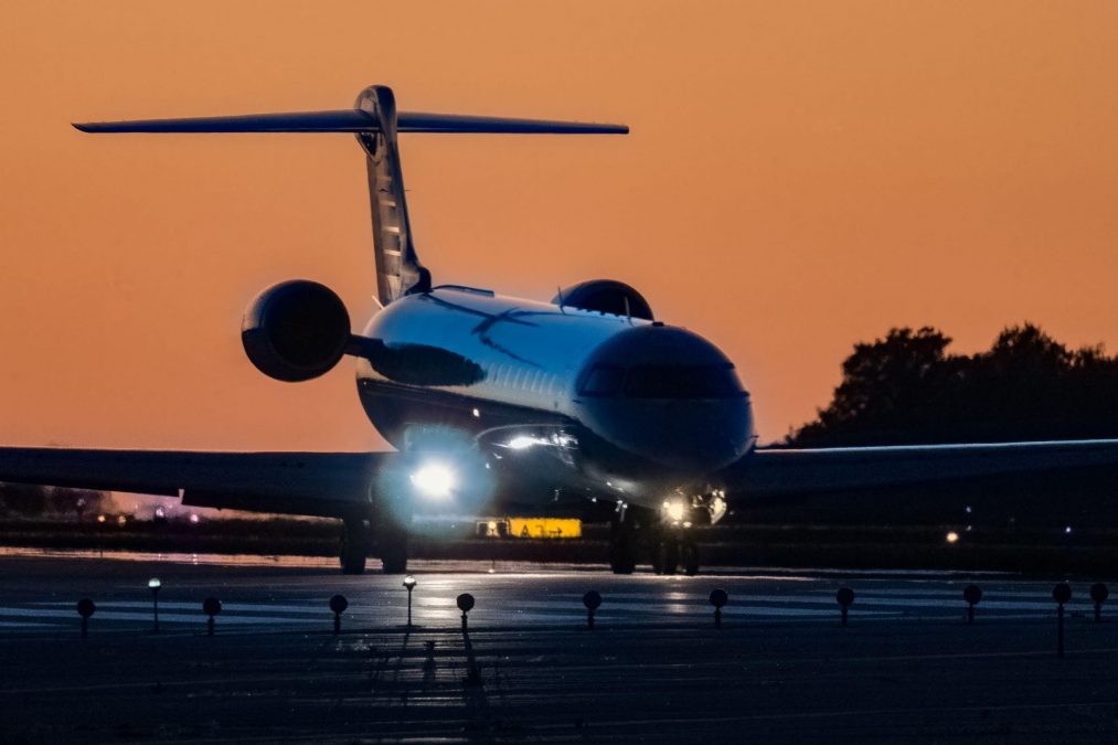 Photo of a plane landing on a runway at sunset