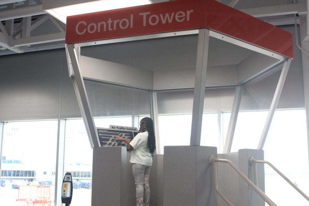 A photo of a girl standing in a playground structure that says "Control Tower"