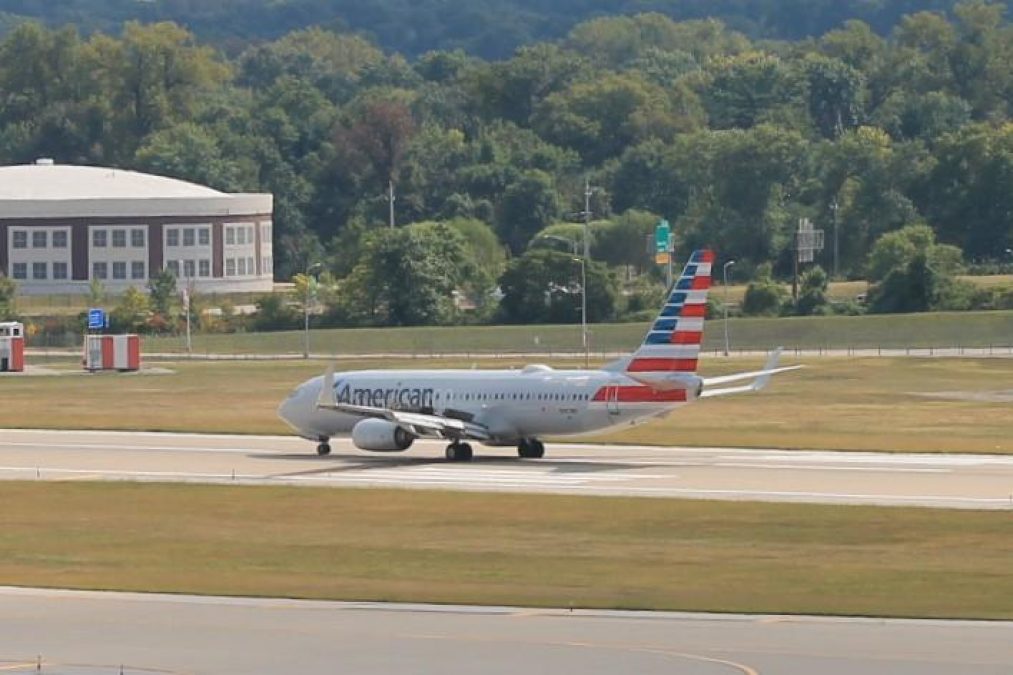 Photo of an American Airlines plane on a runway with trees in the background