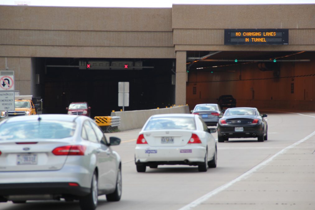 Photo of multiple cars lined up to enter a parking garage in the daytime