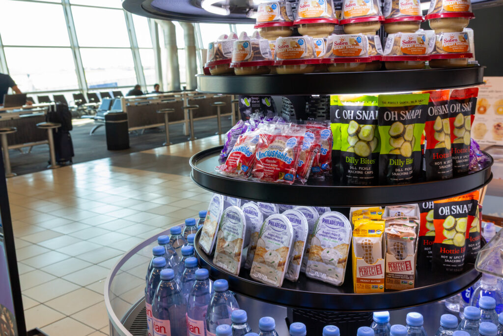 This photo shows the water bottle display as well as refrigerated items such as dill pickles, fruit cups, and Philadelphia Cream Cheese offerings.