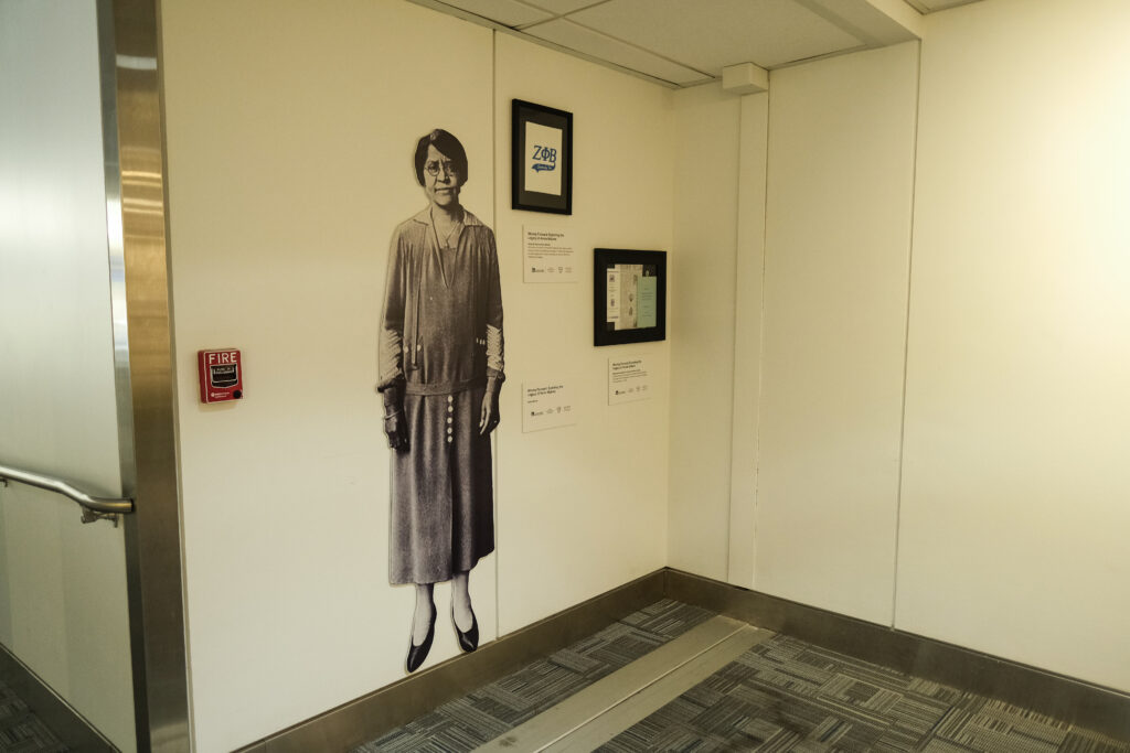 This image shows a section of the Annie Malone exhibit featuring a life-sized black-and-white cutout of her on a wall.
