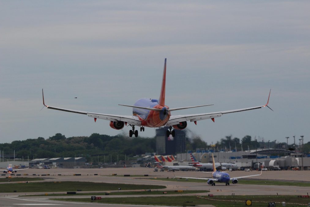 Photo of the back of a plane landing at an airport with other planes in the background