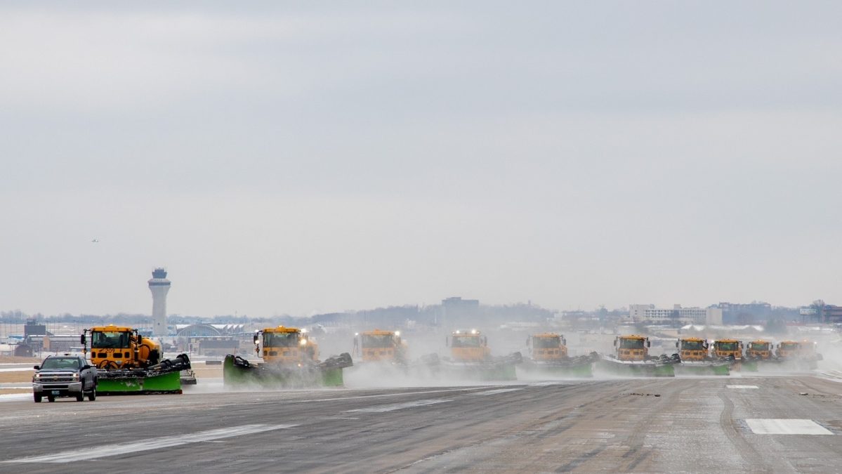 Photo of multiple maintenance vehicles clearing a runway of ice and snow