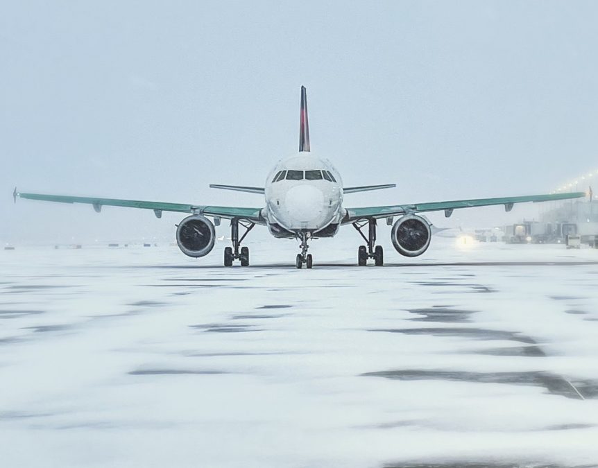 Photo of a plane going down a snowy runway with a white sky behind