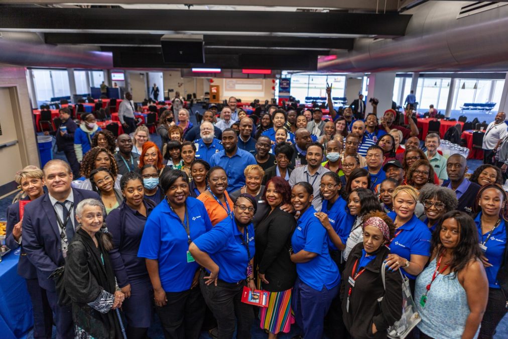 Photo of a room full of people wearing blue shirts posing