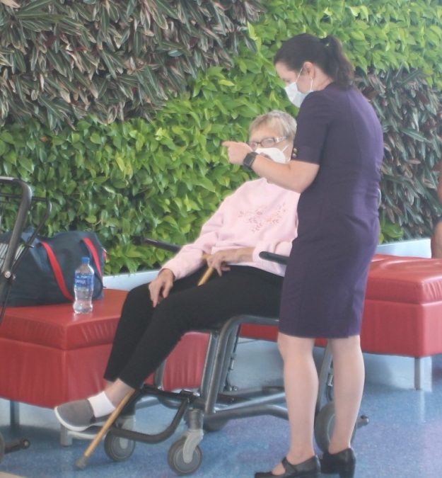 A photo of an airline employee assisting a passenger seated in a wheelchair
