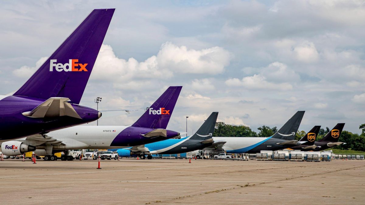 Photo of the backs of several FedEx, Amazon, and UPS planes lined up on a runway