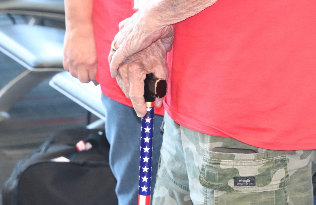 Photo of someone in a red shirt holding an American flag-themed cane