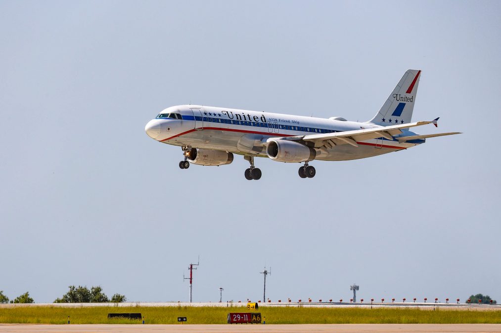 Photo of the side of a United Airbus A320 as it is landing on a runway