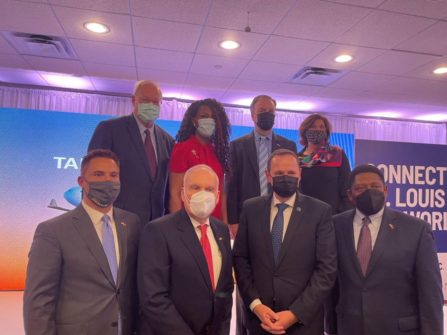 Photo of eight people standing against a backlit backdrop and wearing masks over their noses