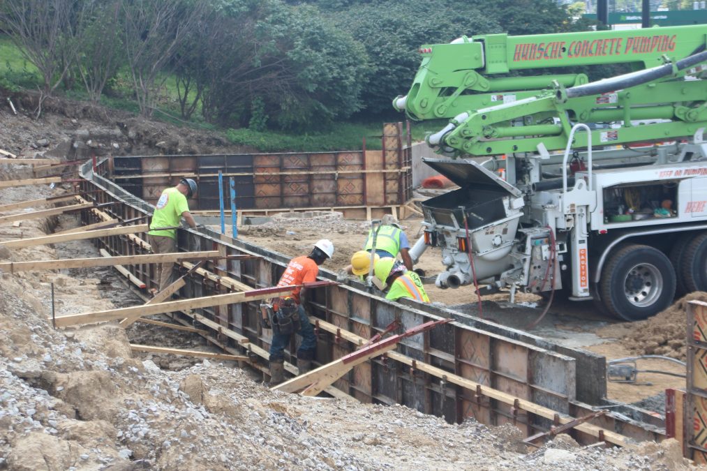Photo of a construction site where multiple workers are appearing to pour concrete