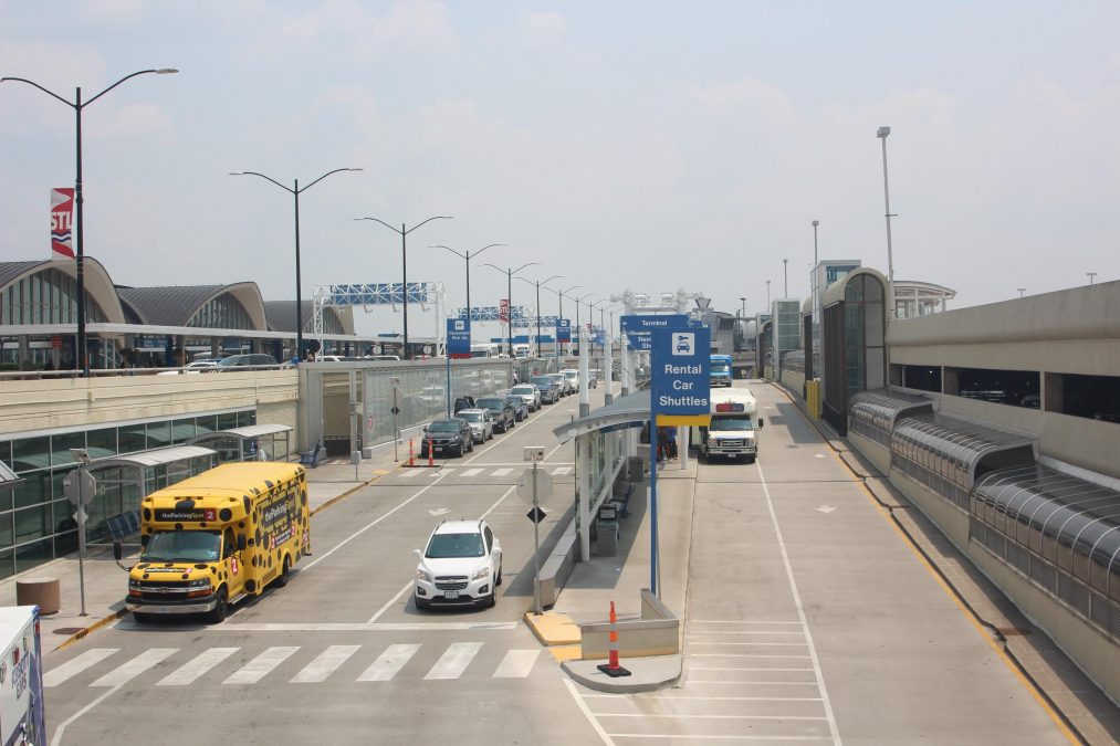 Photo of an airport road with shuttles and cars during the daytime
