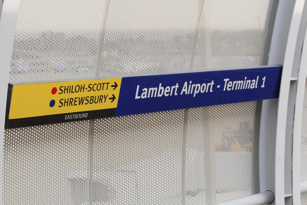Photo of a blue and yellow sign with "SHILOH-SCOTT" and "SHREWSBURY" written on the yellow portion with arrows pointing to the right and "Lambert Airport - Terminal 1" written on the blue side.