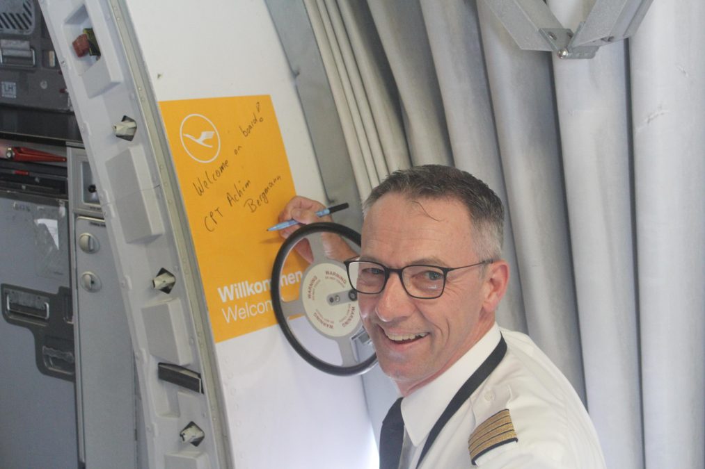 Photo of a captain signing the side of a plane from the inside of a walkway