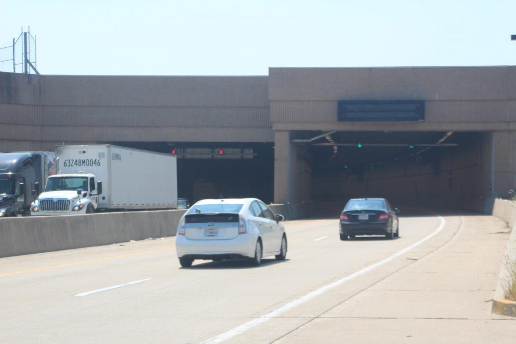 Photo of two cars entering a tunnel and two trucks exiting the tunnel on the opposite side of the road