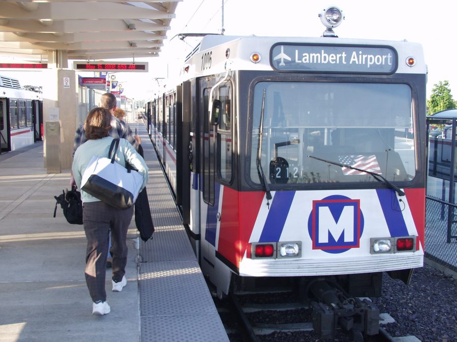 Photo of a bus that says "Lambert Airport" with people walking towards the bus