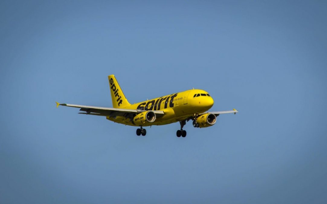 Photo of a yellow Spirit Airlines photo flying against a blue ski background
