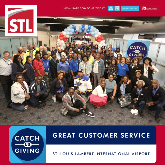 large group of employees and staff from St. Louis Lambert International Airport pose together for a "Catch Us Giving" event celebrating great customer service. They stand under a red, white, and blue balloon arch, with a "Catch Us Giving" sign displayed prominently. The STL logo and a banner reading "Great Customer Service" are shown at the top and bottom of the image.