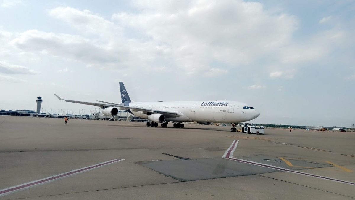Lufthansa Airbus A340-600 being towed on an airport tarmac under a partly cloudy sky.