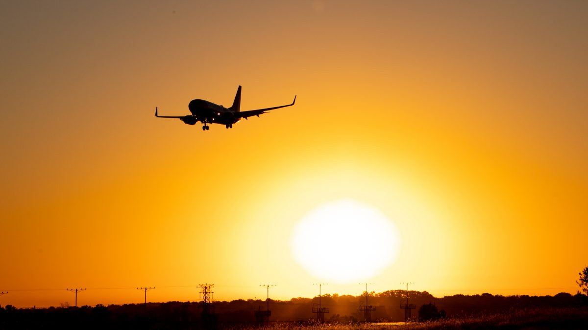 A plane approaches over the sunset.