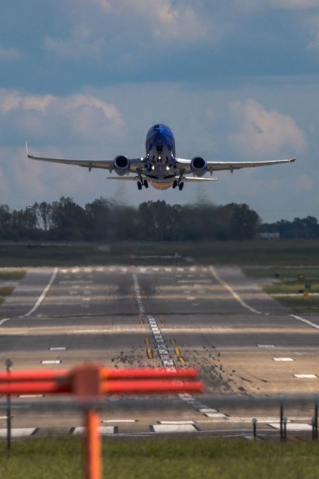 An airplane takes off into flight from the STL tarmac, heading toward the camera.