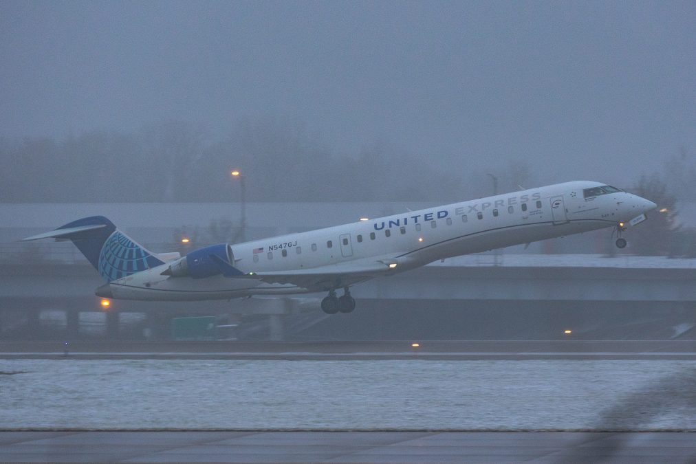 Snow is on the ground while a united express airplane takes off from STL.