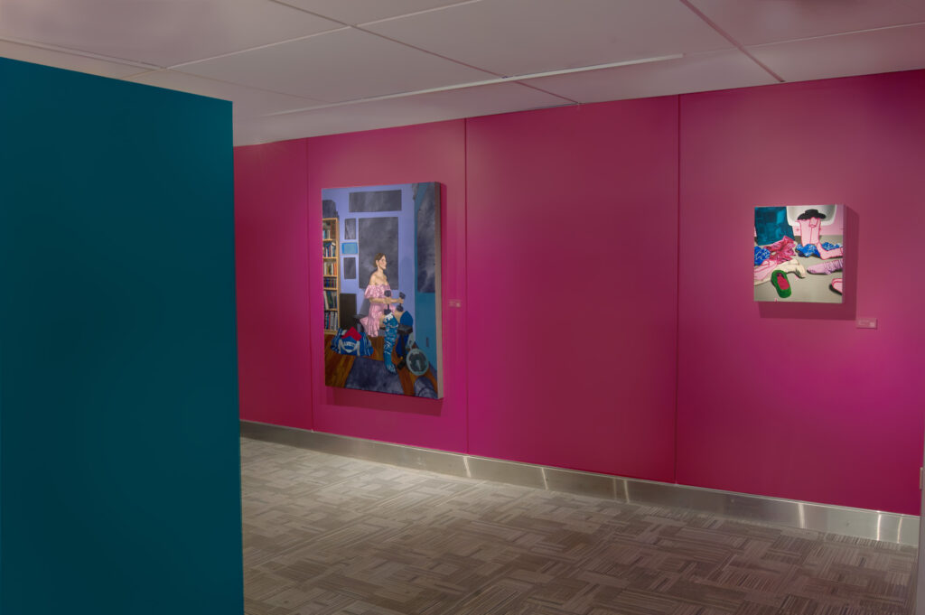 This image displays a gallery space with bold, brightly colored walls. On the bright pink walls are the pieces "510 lb. Leg lift" and "32 Park Dance Routine". The contrasting teal and pink walls enhance the vibrant atmosphere of the exhibit, drawing attention to the vivid colors and dynamic subjects of the paintings.