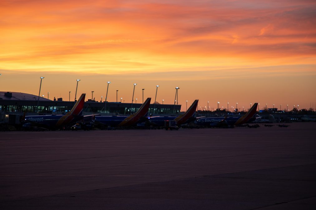 An orange sunset fills the sky overlooking Southwest airplanes at the STL gates.