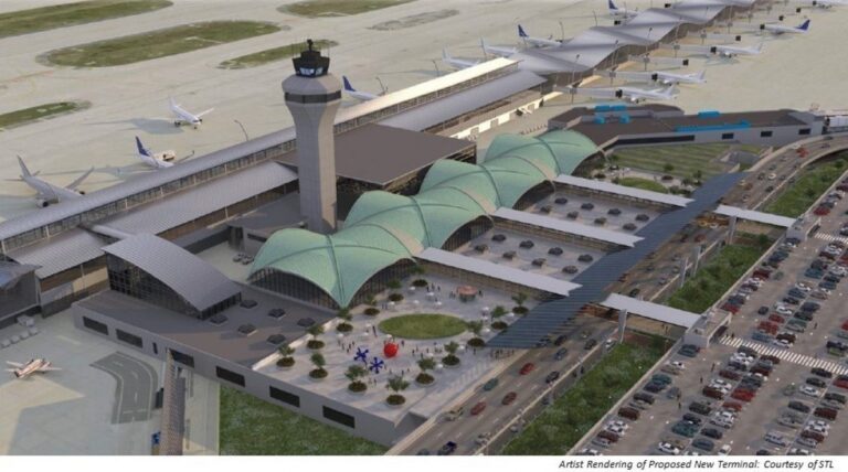 An artist rendering of a proposed new terminal at STL Airport, featuring a large, modern design with several green, arched roofs covering the entrance area. The terminal includes a control tower and multiple concourse gates, where airplanes are parked. A central roundabout, sculptures, and nearby parking structures are visible, alongside a busy multi-lane roadway.