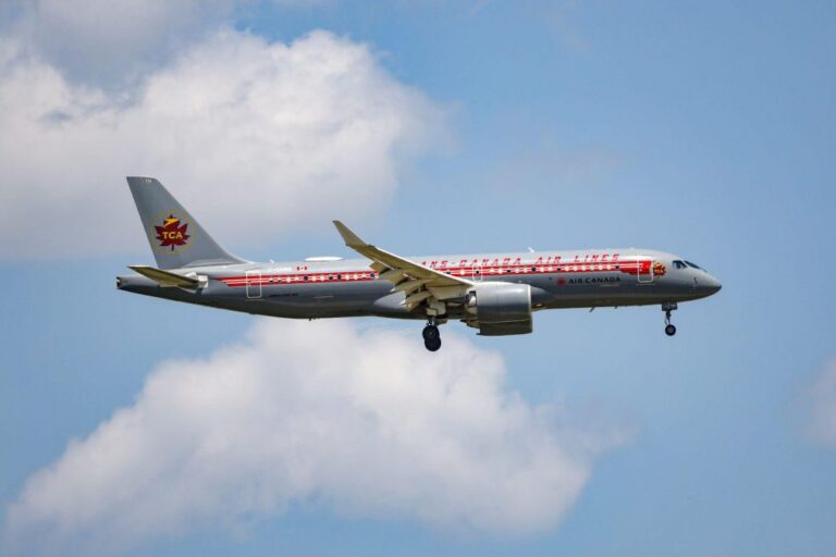 Air Canada passenger jet with a retro Trans-Canada Air Lines livery flying through a partly cloudy sky, landing gear deployed during descent.