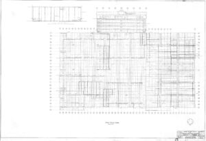 Black and white architectural blueprint of a buildings first floor plan, showing a grid layout with labeled rooms, measurements, and structural details. A scale and title block appear at the bottom right corner.