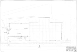 Architectural site plan drawing of a building with detailed outlines, labeled rooms, exterior walls, surrounding pathways, and site boundaries; includes a title block in the bottom right corner and faint grid lines.