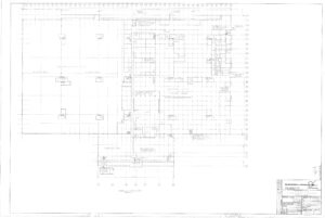 Architectural floor plan drawing of a building, showing grid lines, rooms, walls, doors, and labeled sections. A title block with project details and a scale is located in the bottom right corner.