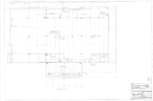 Architectural floor plan drawing showing a large rectangular building layout with rooms, corridors, and detailed measurements. Title block with project information is in the bottom right corner. North arrow is to the lower right.