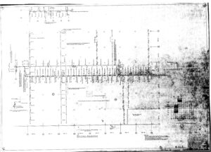 Black and white scanned technical drawing of a building floor plan, featuring labeled measurements, grid lines, symbols, and notes; some areas appear faded or smudged.