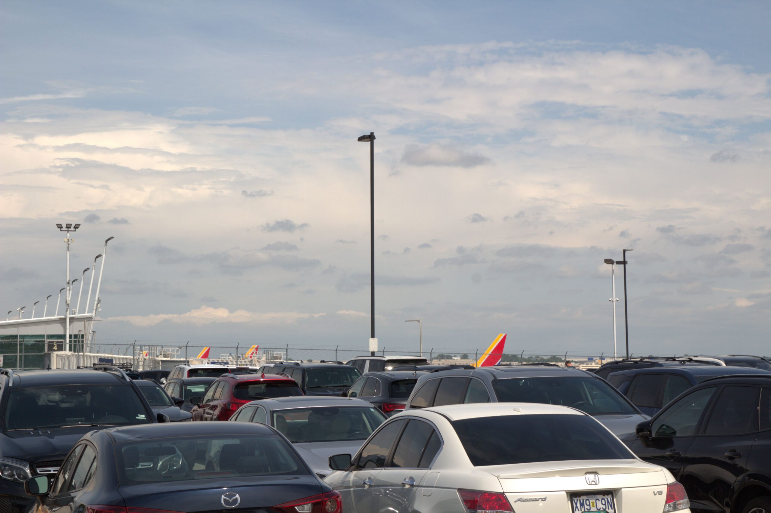 This photo shows Super Park Lot E. The facility is located just east of Terminal 2 and in this photo you see a full lot of automobiles with the Southwest Airline gate tails showing in the background, as the planes are lined up at the gate.