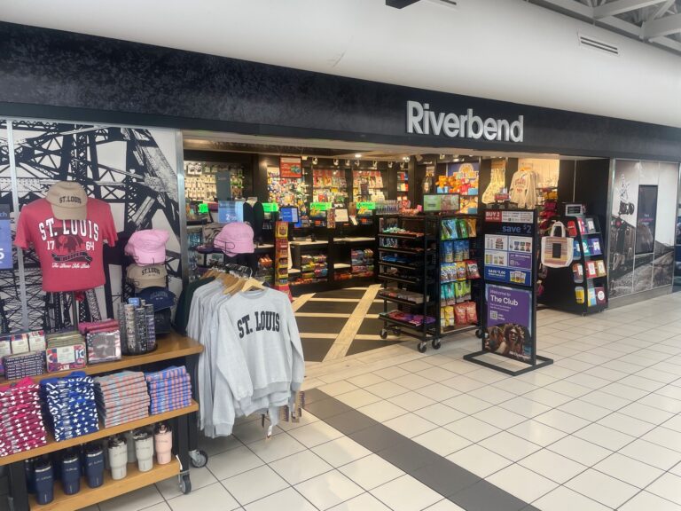 This is the view of the Riverbend market found in STL's Concourse C looking left to right. It shows St. Louis clothing and tumbler souvenirs on the lft to paperback books on the far right. The interior of the store is also shown.