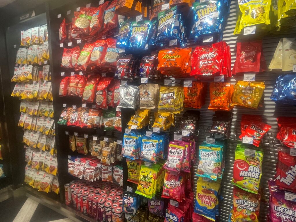 This photo shows the wide variety of snacks available at the Riverbend market. The back wall of the shops has six rows and a bottom shelf with a wide variety of products.