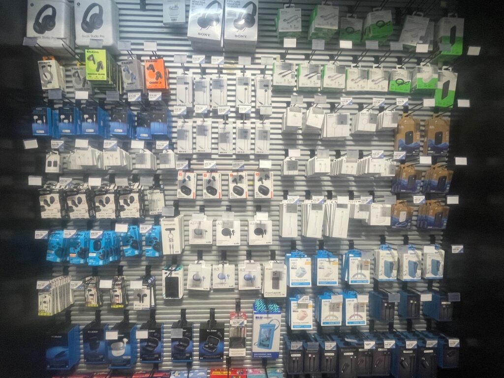 This photo shows the wide variety of electronic accessories available at the Riverbend market. This wall display has eight rows and a bottom shelf showcasing a wide variety of products from ear buds to USB to c-USB cords.