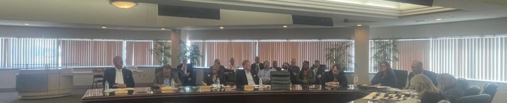 This is photo was taken in the Lindbergh Conference Room of the STL Airport Commission Meeting taken on September 2, 2026. This photo is a a number of members seated around the conference room table and Jerry Beckmann, the Interim Airport Director chairing the meeting.