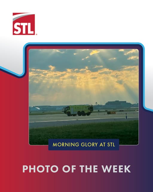 A green airport fire truck drives on a runway at sunrise under partly cloudy skies, with sunbeams breaking through the clouds.