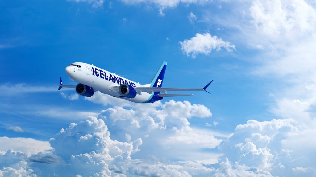 This is a photo of an Icelandair 737MAX8 traveling through the clouds a blue sky.