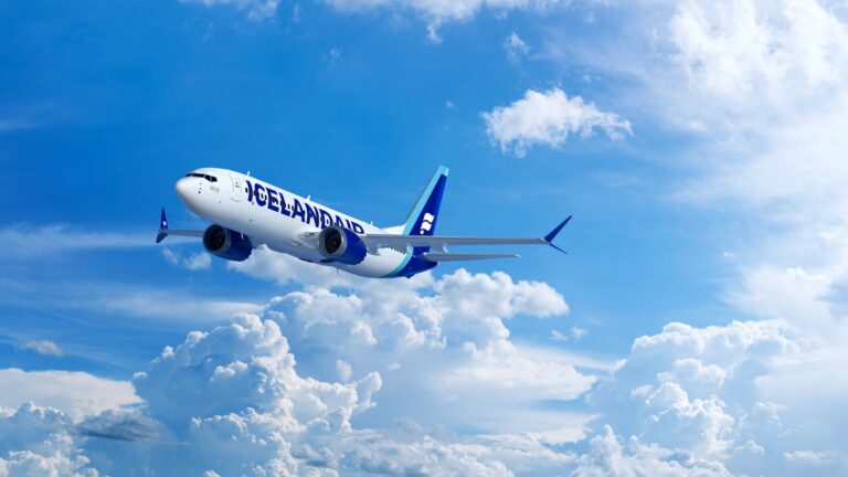 This is a photo of an Icelandair 737MAX8 traveling through the clouds a blue sky.