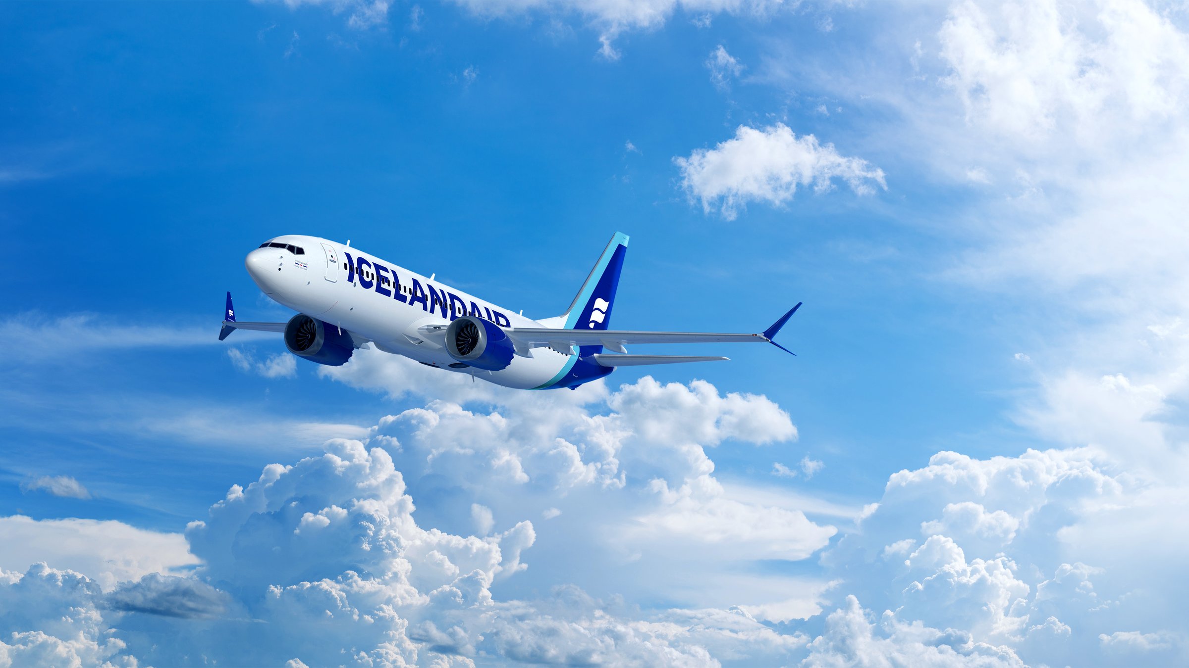 This is a photo of an Icelandair 737MAX8 traveling through the clouds a blue sky.